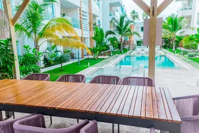 a wooden table and chairs next to a swimming pool at Apartamento en punta cana close to the beach in Punta Cana