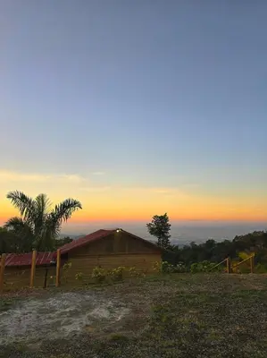 a barn on a hill with a sunset in the background at Mountain refuge - Cabin with wonderful views! in La Búcara