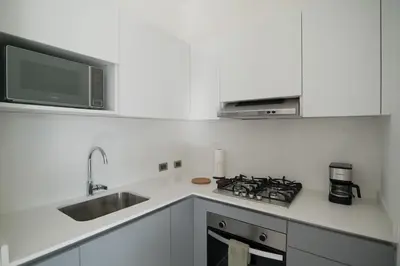 a white kitchen with a sink and a microwave at La Anshihi in Las Terrenas