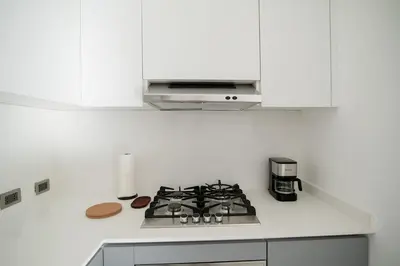 a white kitchen with a stove and a microwave at La Anshihi in Las Terrenas