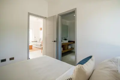 a bedroom with a white bed and a door to a living room at La Anshihi in Las Terrenas