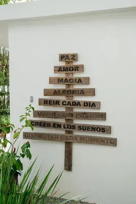 a directional sign with names on it next to a wall at La Anshihi in Las Terrenas