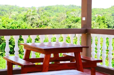 a wooden table and benches on a balcony with a view at Apart hotel Costa Verde#7 con cama Queen in Las Galeras