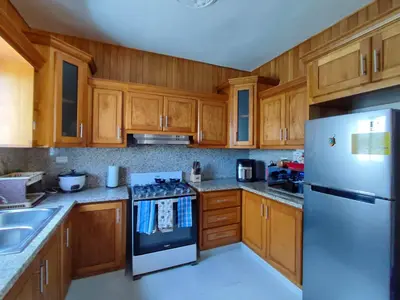 a kitchen with wooden cabinets and a stainless steel refrigerator at Sol, playa y arena, Casa cerca de la playa in San Felipe de Puerto Plata
