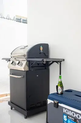 a grill with a bottle of beer on top of it at Sol, playa y arena, Casa cerca de la playa in San Felipe de Puerto Plata
