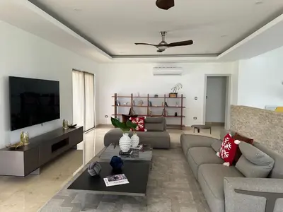 a living room with a couch and a tv at Villa paraíso in Juan Dolio