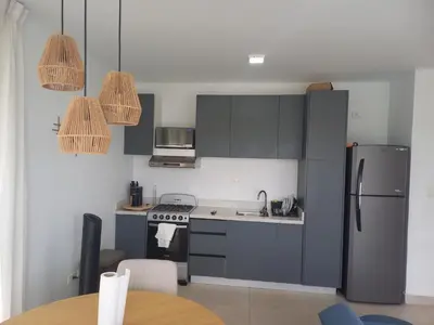a kitchen with gray cabinets and a refrigerator and a table at Apartamento en Vista Cana in Batey San Germán