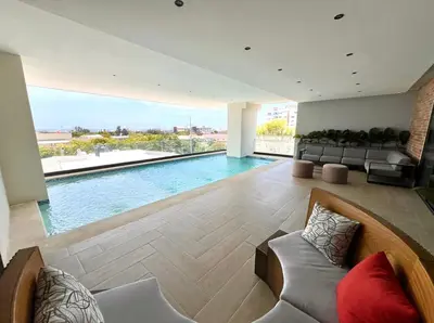 a living room with a swimming pool and a couch at Comfortable apartmento en el centro de la ciudad con piscina y gym in Santo Domingo