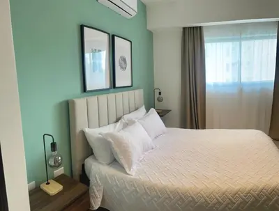 a bedroom with a bed with white sheets and pillows at Comfortable apartmento en el centro de la ciudad con piscina y gym in Santo Domingo