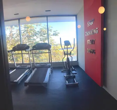 a gym with three tread machines and a window at Comfortable apartmento en el centro de la ciudad con piscina y gym in Santo Domingo