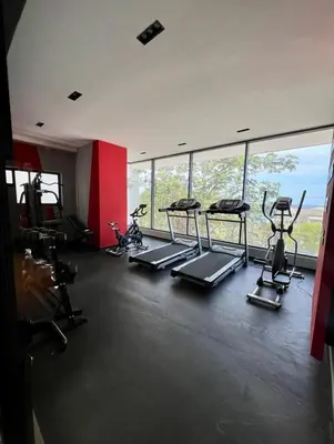 a gym with several tread machines in a room with windows at Comfortable apartmento en el centro de la ciudad con piscina y gym in Santo Domingo