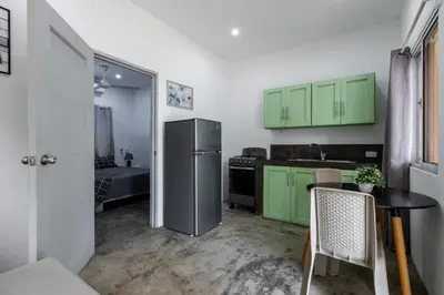 a kitchen with green cabinets and a table and a refrigerator at El Patio de Lucia Residencia in Las Terrenas