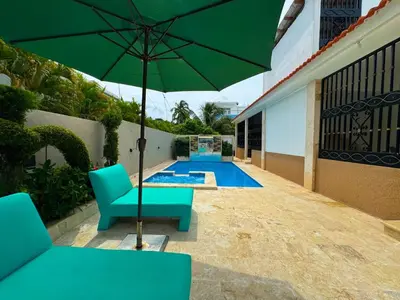 a patio with a green umbrella and chairs and a pool at Villa luxury Cabarete in Cabarete