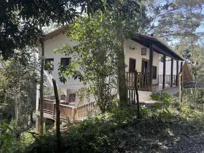 a small white house with a porch and trees at Villa Jarabacoa Monte Bonito in Jarabacoa