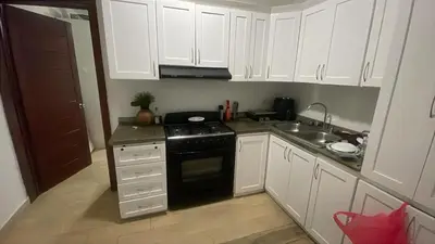 a kitchen with white cabinets and a black stove at Apartamento amueblado a 5 minutos de la playa in Bayahibe