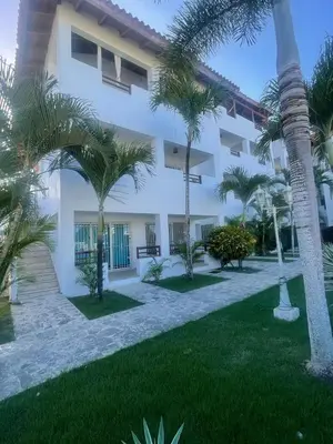 a white building with palm trees in front of it at Apartamento amueblado a 5 minutos de la playa in Bayahibe