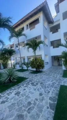 a white building with palm trees in front of it at Apartamento amueblado a 5 minutos de la playa in Bayahibe