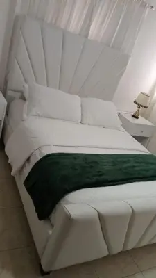 a white bed with a green blanket on it at Casa con piscina Romana del Oeste in La Romana
