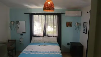 a bedroom with a bed with a window and a lamp at Kassuky Home in Cabarete