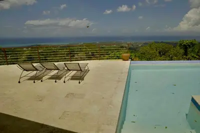 a group of chairs sitting on the edge of a swimming pool at Villa Lukner Las Terrenas in Las Terrenas