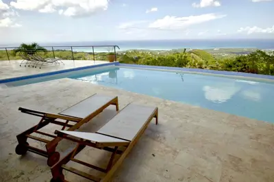 a swimming pool with two lounge chairs next to it at Villa Lukner Las Terrenas in Las Terrenas
