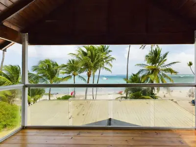 a room with a view of a beach and palm trees at The Ocean Front Palomar in Punta Cana