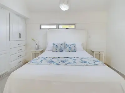 a white bedroom with a large white bed with blue pillows at The Ocean Front Palomar in Punta Cana