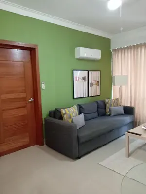 a living room with a blue couch and green walls at Céntrico y acogedor apartamento en Bella Vista in Santo Domingo
