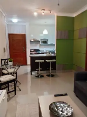 a living room with green walls and a kitchen at Céntrico y acogedor apartamento en Bella Vista in Santo Domingo