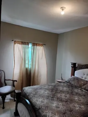 a bedroom with a bed and a chair and a window at Villa Magante in La Yagua