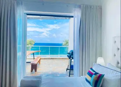 a bedroom with a view of the ocean through a sliding glass door at Beachfront Luxury Penthouse in Sosúa