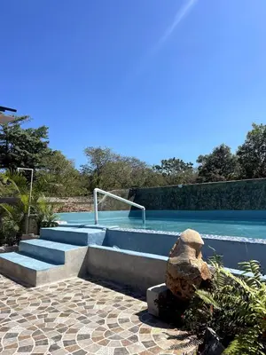 a swimming pool with some stairs and a rock at Habitacion 3 en Dani's Guest House in Las Galeras