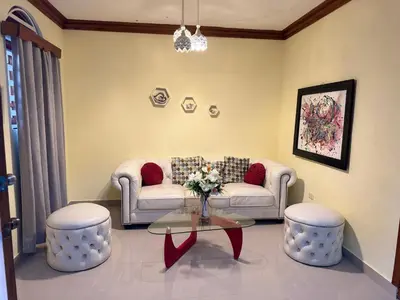 a living room with a couch and two stools at Hotel El Bonao in Higuey