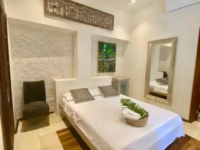 a bedroom with a bed with a chair and a mirror at Boutique Hotel Casa Grande, Parrot's Paradise Suite in Santo Domingo