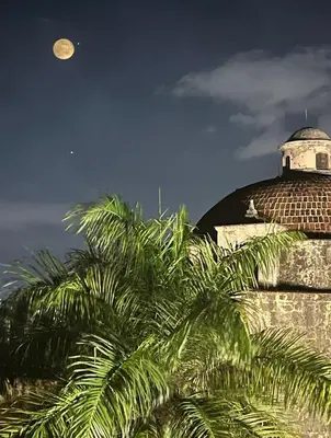 a moon over a building with palm trees in the foreground at Luxury Two-Level Townhouse with Stunning Historic Views in Santo Domingo