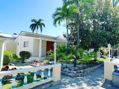 a house with palm trees in front of it at Villas Jazmin in San Felipe de Puerto Plata