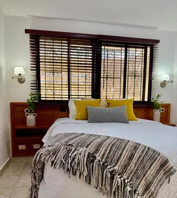a bedroom with a large bed with yellow pillows at Villas Jazmin in San Felipe de Puerto Plata