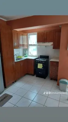 a kitchen with wooden cabinets and a black stove at Edificio maremma 6 in Boca Chica