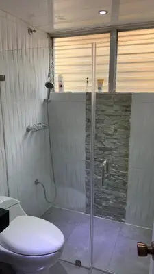 a bathroom with a toilet and a glass shower at Comfortable apartment in Santo Domingo