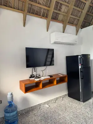 a flat screen tv on a wall next to a black refrigerator at Charming Bungalow with Pool in Sosúa