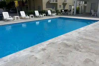 a swimming pool with lounge chairs next to a building at Sunshine Palmares de Caleta in La Romana