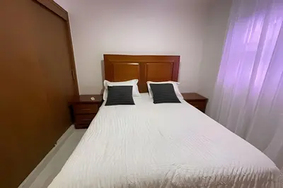 a bedroom with a white bed with two black pillows at Sunshine Palmares de Caleta in La Romana