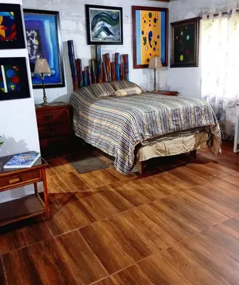 a bedroom with a bed and a wooden floor at Chalet Thevenin Art Accommodation in Jarabacoa
