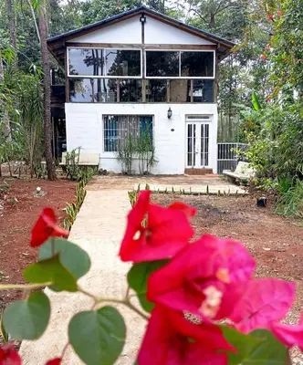 a house with red flowers in front of it at Chalet Thevenin Art Accommodation in Jarabacoa