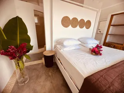 a bedroom with a bed with flowers in a vase at Villa blanca chambre d'hôtes vue sur mer in Las Terrenas