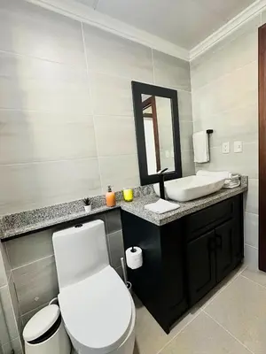 a bathroom with a toilet and a sink and a mirror at Eden Caribe Condo, Bavaro Punta Cana in Punta Cana