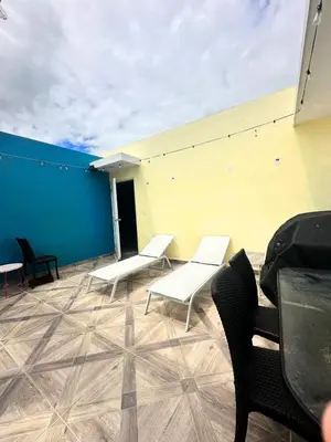 a patio with white benches and a blue and yellow wall at Eden Caribe Condo, Bavaro Punta Cana in Punta Cana