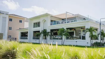 a white house with palm trees in front of it at Luxury Apt with Pool Golf View in Hard Rock Golf in Punta Cana