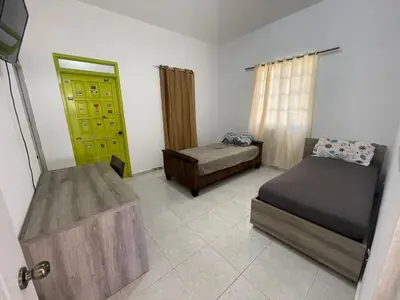 a small bedroom with two beds and a door at Villa with Oceanviews for All Types of Travelers in San Felipe de Puerto Plata