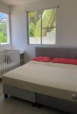 a bedroom with a bed with two red pillows and a crib at Villa with Oceanviews for All Types of Travelers in San Felipe de Puerto Plata